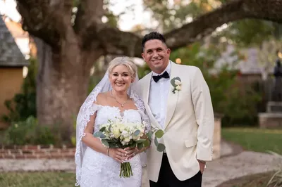 Amanda and Max pose together in front of Lightner Museum during St Augustine's Nights of Lights, the bride's lace train flowing beautifully.
