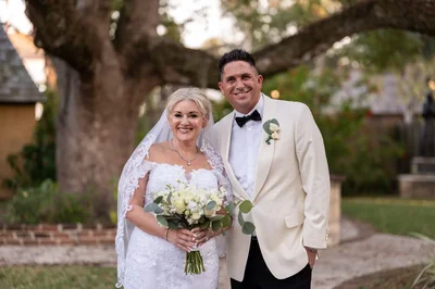 Amanda and Max pose together in front of Lightner Museum during St Augustine's Nights of Lights, the bride's lace train flowing beautifully.