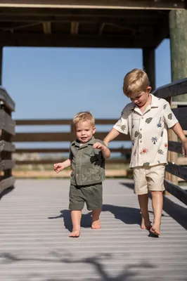Two young children walking hand in hand across the wooden boardwalk at Mussallem Beachfront Park