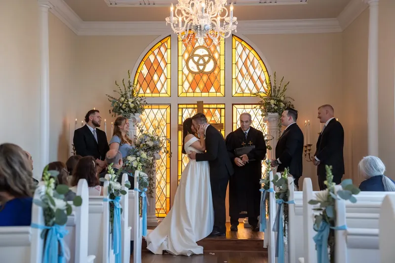 The couple holds hands at the center of the aisle as family members stand nearby during their ceremony.