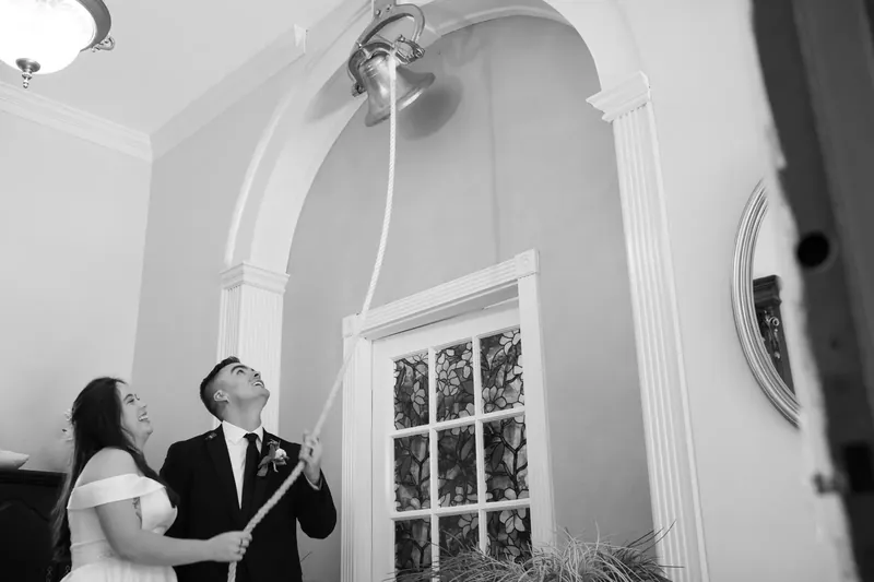 Ana and Bailey exchange vows beneath an arched ceiling at Amore Wedding Chapel, silhouetted by natural light.