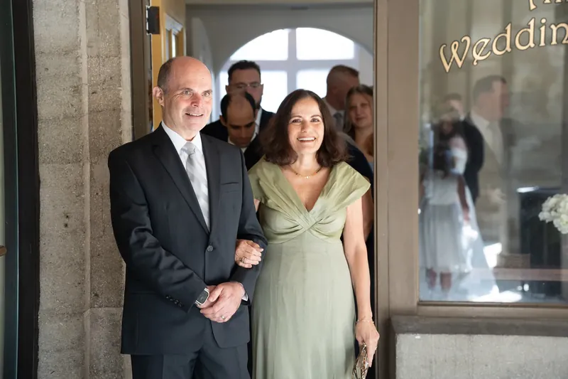 Ana and Bailey walk arm-in-arm through the chapel entrance as guests watch them depart as a married couple.