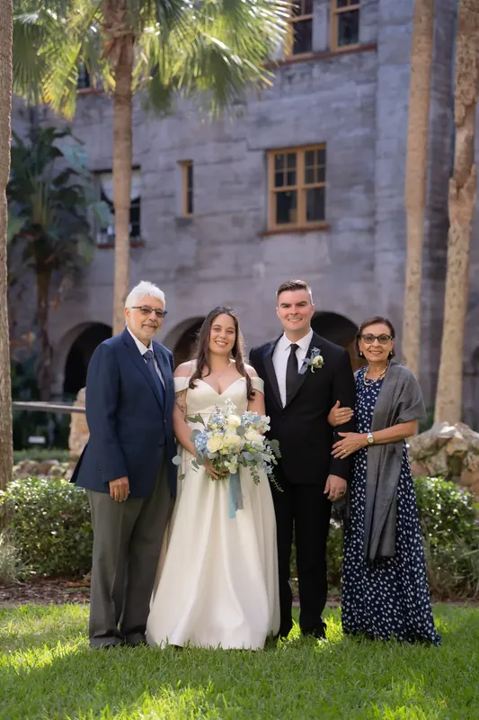 Ana holds a white bouquet while standing with three family members on the lawn at Lightner Museum.