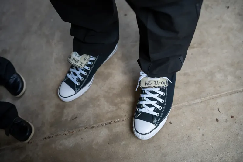 Black canvas sneakers with white socks peek from black dress pants on the pavement at Lightner Museum.