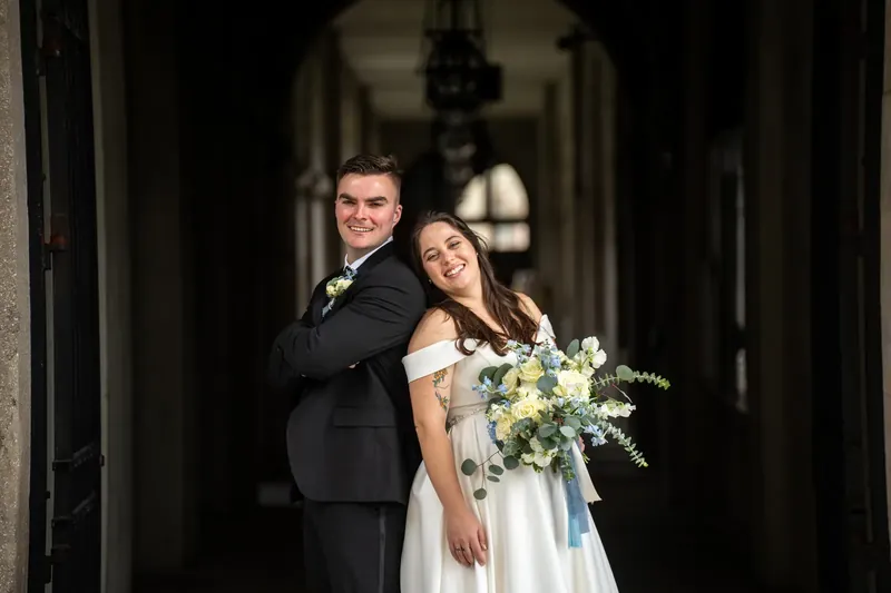Bailey wraps an arm around Ana as they laugh together in the columned corridor at Lightner Museum.