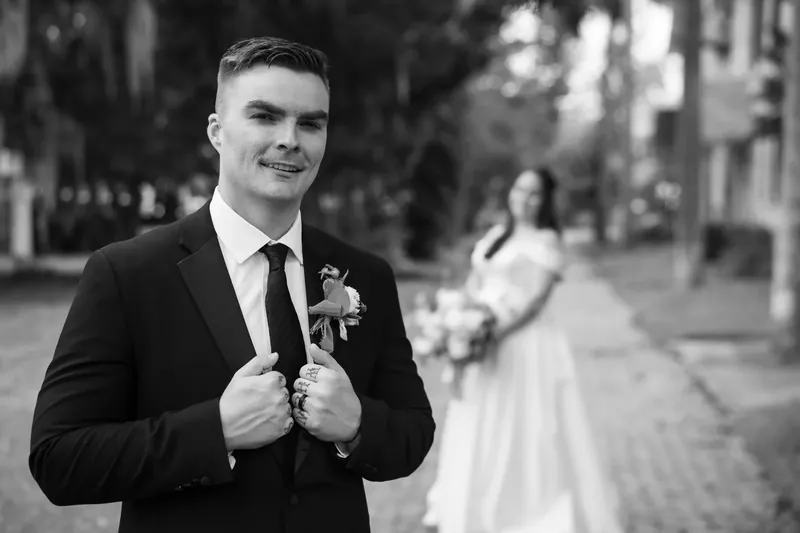 Ana and Bailey face each other in a vaulted stone corridor, holding a white floral bouquet between them.