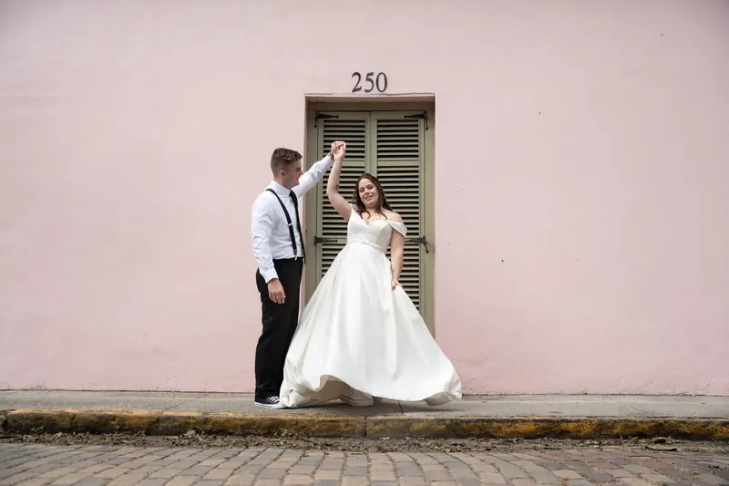 Bailey reaches toward Ana as she twirls her white gown in front of the museum's arched doorway numbered 250.