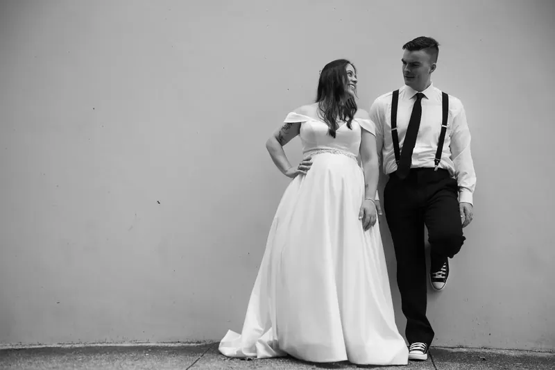 Ana and Bailey pose in black and white, she with hand on hip and he gazing toward her.