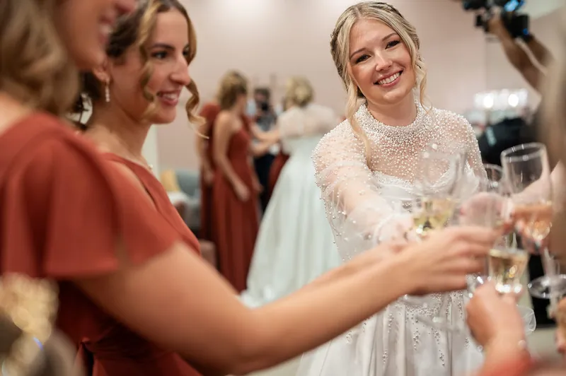 A guest in a rust-colored dress smiles while Anna holds a champagne flute at The Treasury on the Plaza.