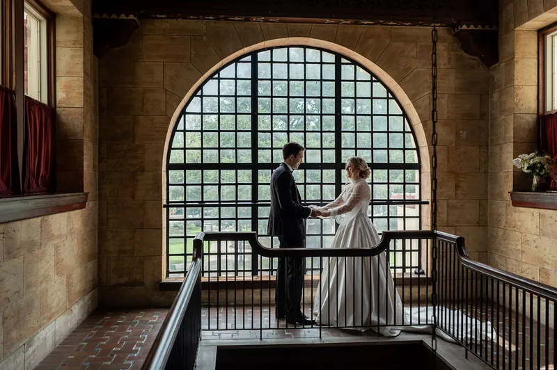 Anna and Rafael exchange vows at a large arched window at The Treasury on the Plaza.
