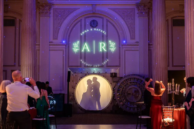 Anna and Rafael's silhouettes are projected on a screen during their first dance, framed by neon "AIR" lettering and purple