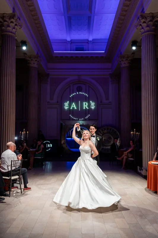Anna dances solo in her flowing white gown across the illuminated ballroom floor, surrounded by columns and purple ambient
