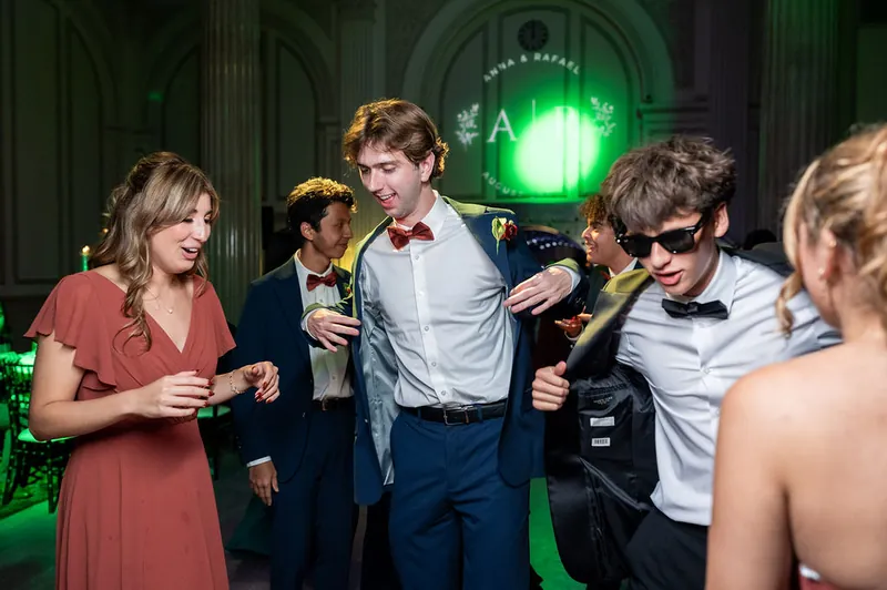 Guests dance and celebrate under green stage lighting in the historic venue's columned hall during the reception.