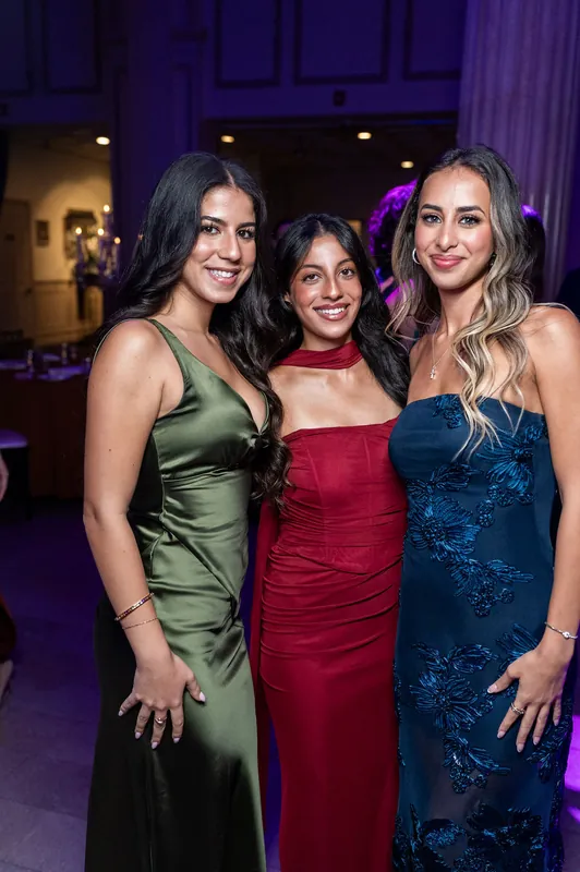 Three women in jewel-toned gowns smile together during the reception at The Treasury on the Plaza, St. Augustine.