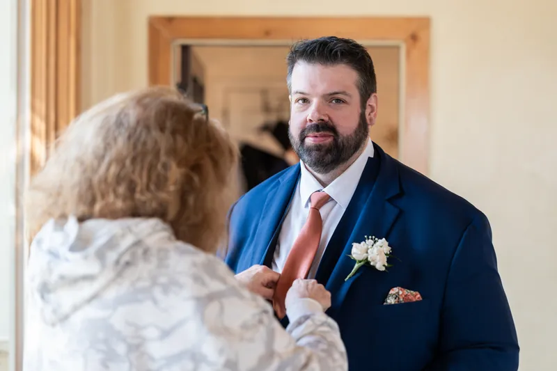 The groom's mother adjusting his tie before the ceremony