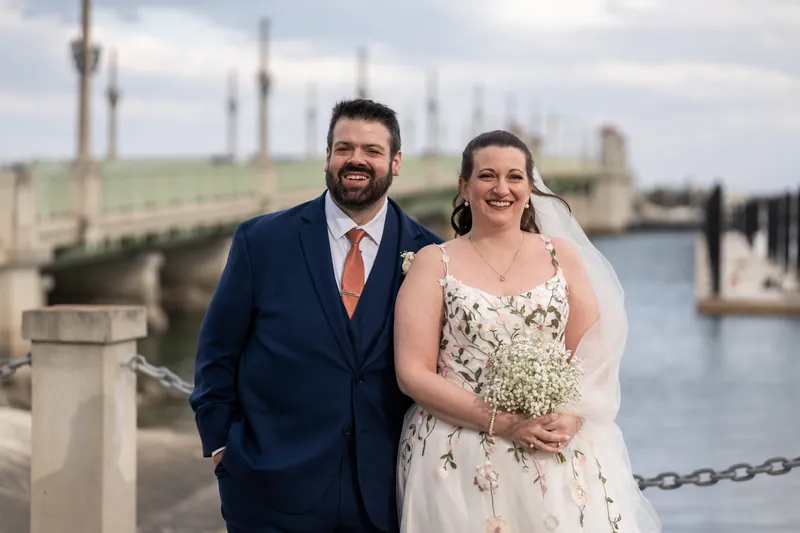 The couple laughing together along the St. Augustine bayfront with the Bridge of Lions in the background
