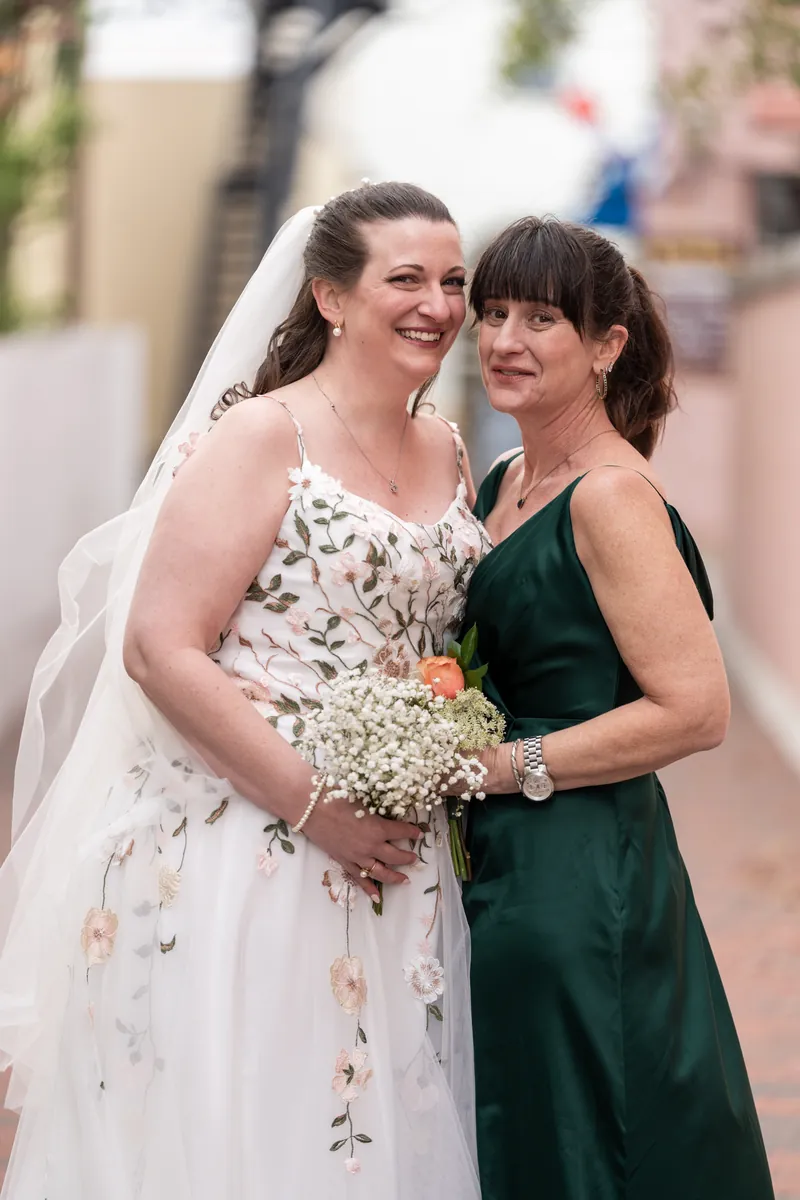 The bride and her maid of honor posing together on a downtown St. Augustine sidewalk, both smiling warmly