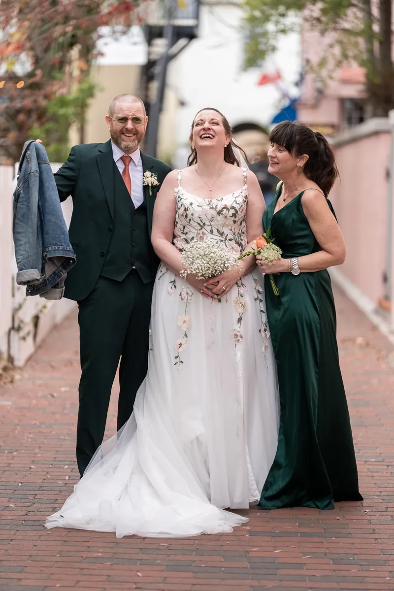 The bride laughing between her best man and maid of honor as they walk down a brick-paved alley in St. Augustine