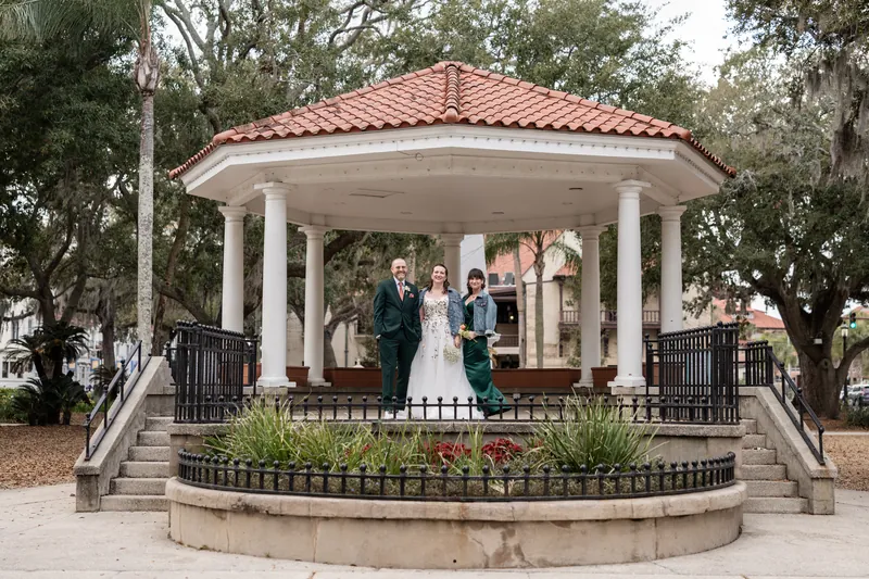 The wedding party standing together at the Plaza gazebo in St. Augustine, framed by oak trees