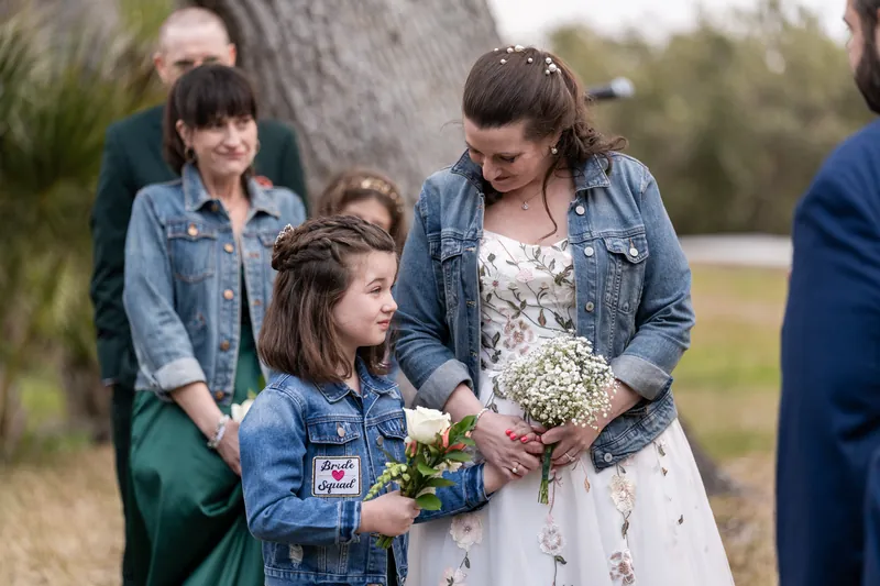 The bride looking down at her daughter during the ceremony as the maid of honor watches from behind
