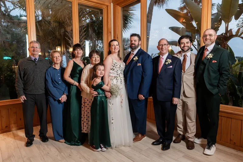 A family group portrait in front of the reception pavilion's floor-to-ceiling windows at Fountain of Youth