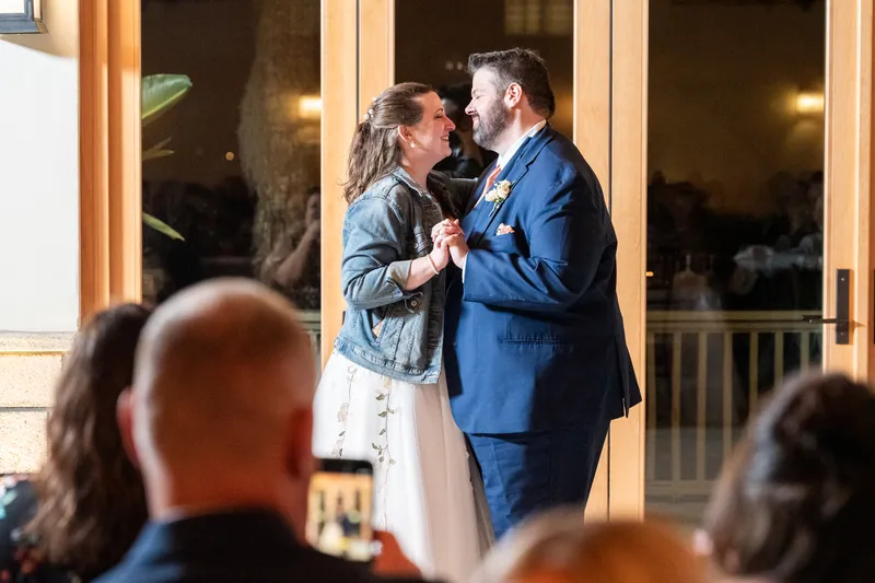 Anne and Chase sharing their first dance in the Fountain of Youth pavilion, smiling at each other as guests watch