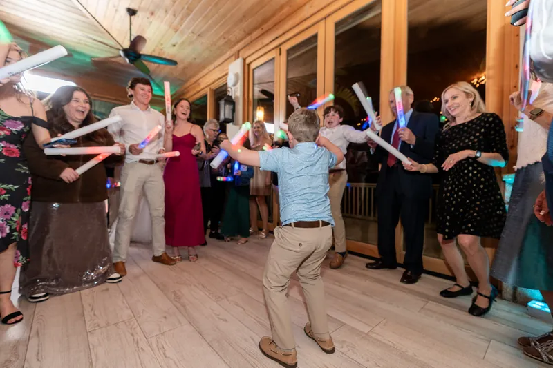 Guests dancing with LED glow sticks on the reception dance floor as a young guest shows off his moves in the center
