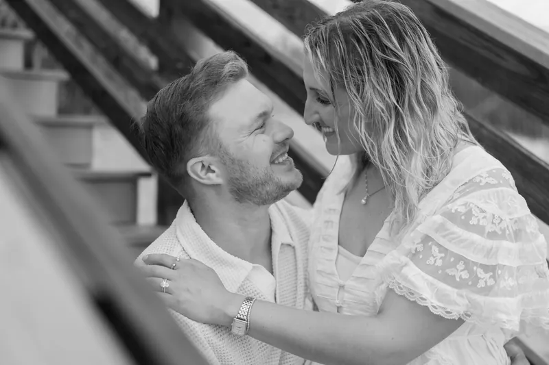 Craig and Ashley embrace on the beach, their faces close as waves crash behind them at Vilano Beach.