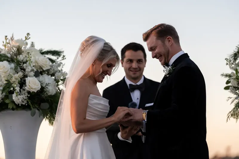 Ashley and Craig hold hands during the ring exchange as the officiant looks on.