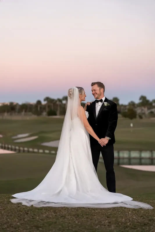 Ashley and Craig pose at dusk with the golf course and resort reflected in the background.