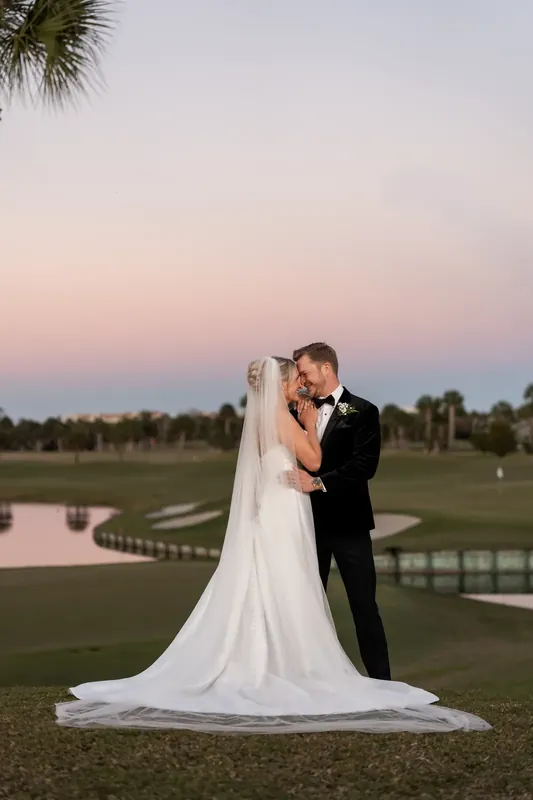 Craig dips Ashley across the fairway as her white gown train flows toward the ground.