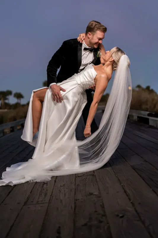 Craig dips Ashley on a rooftop as her veil streams in the wind at Sawgrass Marriott.