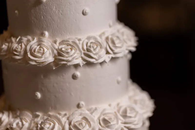 Close-up detail of white rosette piping and pearl beading on a tier of the couple's tiered wedding cake.