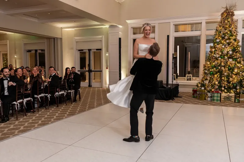 Craig dips Ashley mid-dance as a decorated Christmas tree glows nearby and guests look on.