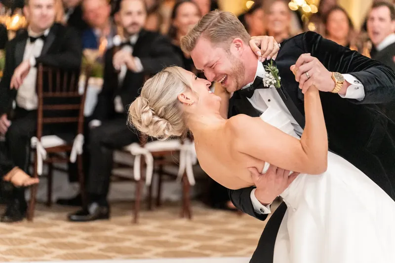 Craig bends backward while dancing with Ashley, who holds his shoulder with a joyful expression.