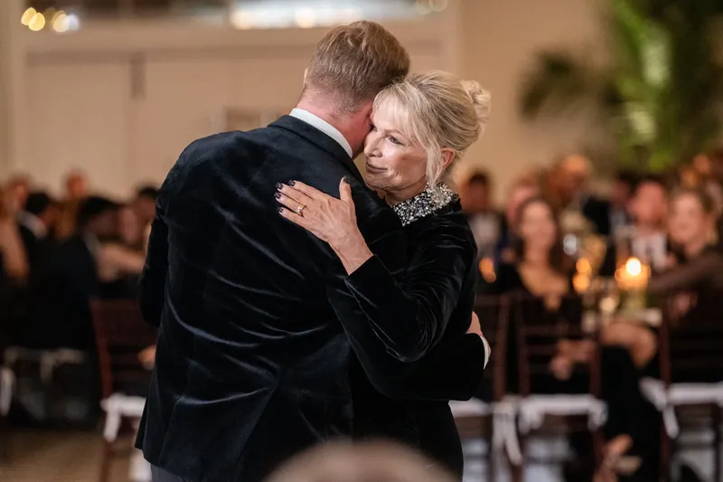 The two embrace on the dance floor as guests look on during their reception.