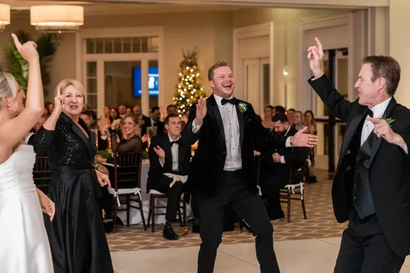 Ashley in her white gown dances with Craig and another guest as the crowd watches and celebrates.