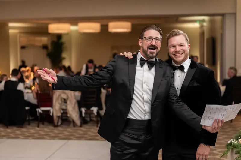 Two men in tuxedos embrace and smile during the celebration.
