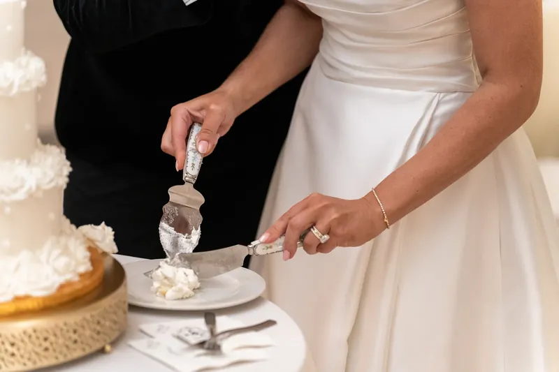 Ashley and Craig cut their cake together, hands overlapping on the knife.