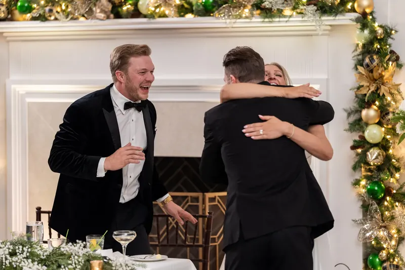Craig embraces a guest while another person looks on at the reception.