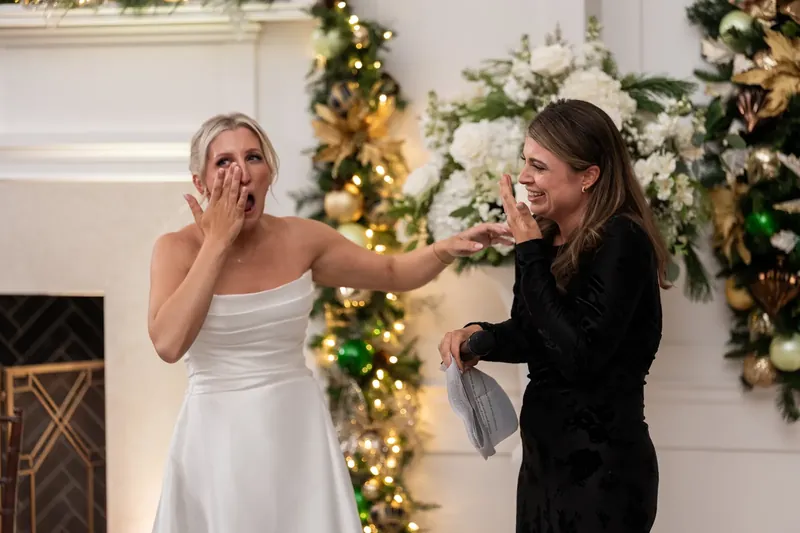 Ashley covers her mouth in surprise as a woman reaches toward her during the reception.