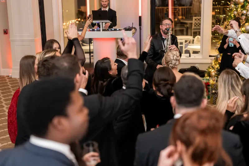 A DJ stands at the booth while guests crowd the dance floor, celebration and music filling the room.