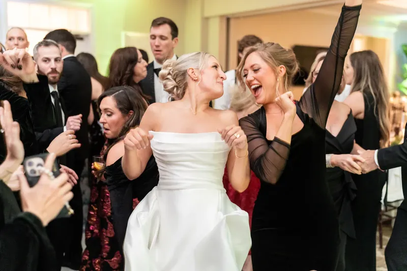 Ashley grins between two women as guests celebrate around them on the dance floor.