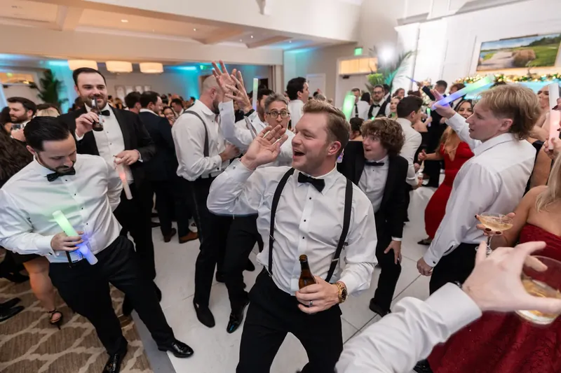 Craig grins amid cheering guests in a ballroom filled with wedding reception attendees in formal attire.