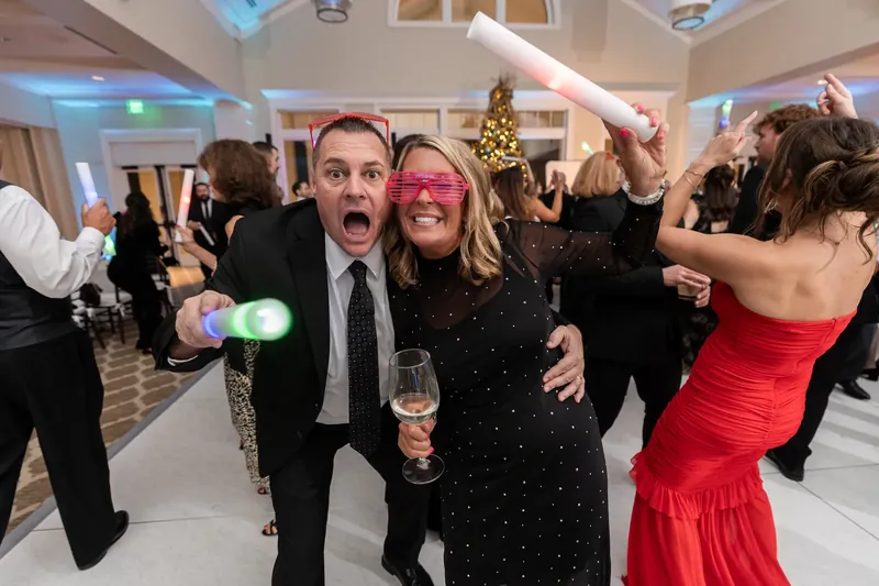 Craig and a guest in pink sunglasses laugh together while holding drinks on the dance floor.