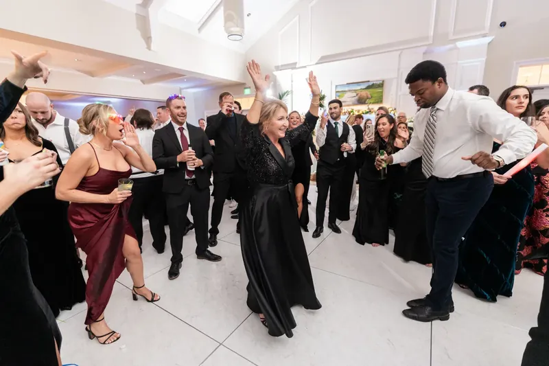 Guests dance and mingle across the brightly lit reception space in coordinated formal wear.