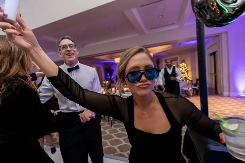 Guests dance and celebrate on the ballroom floor while purple uplighting illuminates the Sawgrass Marriott reception space around them.