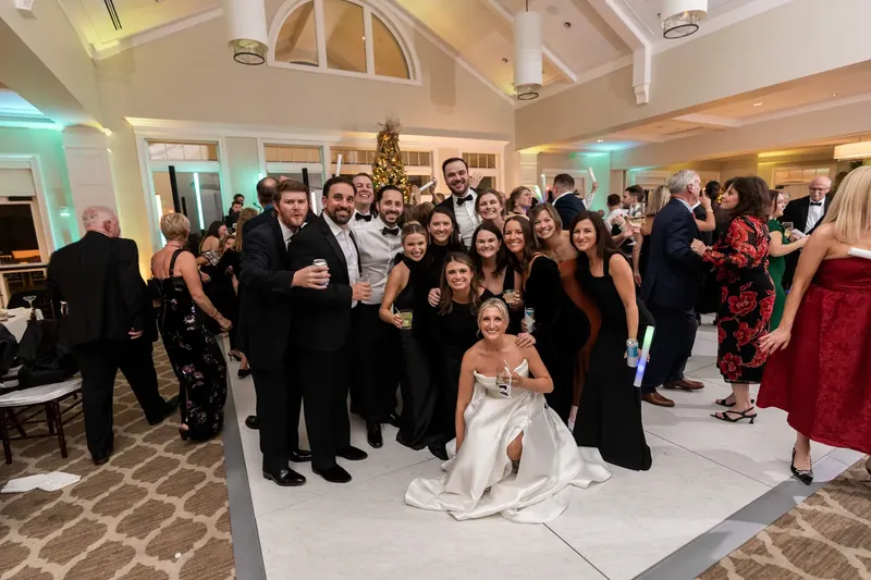 The full wedding party gathers on the dance floor for a group photo at the Sawgrass Marriott.