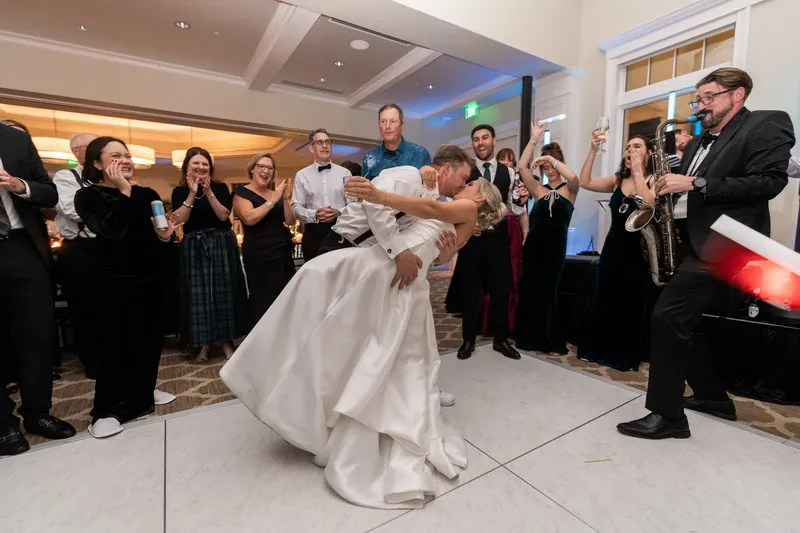 Craig dips a guest in a white gown while the ballroom crowd cheers and watches the moment unfold.