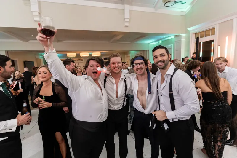 Craig raises his fist triumphantly while surrounded by groomsmen in white shirts and ties at the Sawgrass Marriott.